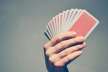 يد تمسك بمروحة من أوراق اللعب